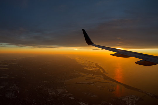 airplane flying above the clouds over New York at sunset