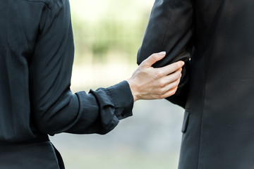 cropped view of woman touching hand on man on funeral