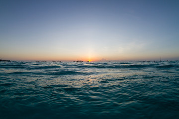 sunset over the ocean with ship silhouettes