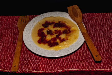 Plate of polenta, organic Italian food with milk, pumpkin and cheese, and red sauce with tomato and fresh basil. Horizontal studio shot.