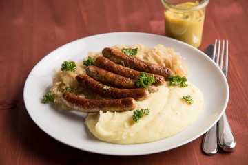 Kleine Bayrische Nürnberger Rostbratwürste mit Sauerkraut, Kartoffelpüree und Senf auf Holz Tisch Hintergrund