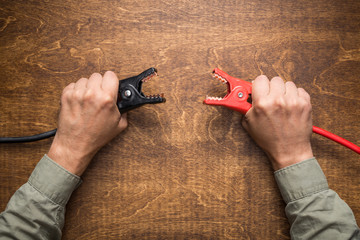 Hands holding battery charging clamps