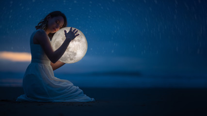 Tender image of a girl; female magic. Beautiful attractive girl on a night beach with sand and...