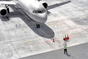airplane arrival to airport runway aerial top down front closeup view of modern passenger plane arriving to terminal gate with maintenance worker person guiding to park aircraft for disembarkment