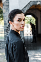 attractive woman in black formal wear looking at camera on funeral