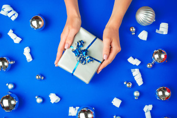 Female hands with gift box on a blue background