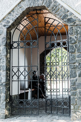 upset man and woman sitting near metallic gates in cemetery
