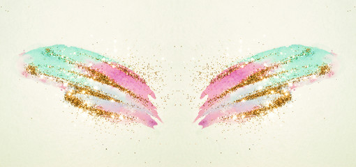 Golden glitter on abstract pink and blue watercolor wings in vintage nostalgic colors.