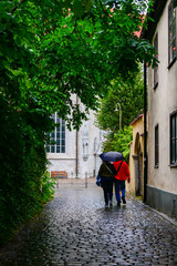 Fototapeta na wymiar Visby, Gotland, Sweden A couple walk on the back streets of the medieval cityin the rain.