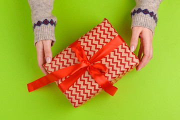 Woman hands holding gift box on green background