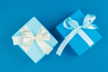 Flat lay of gift box decorated with bow on blue background