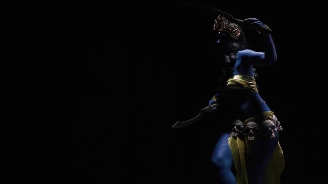 Indian goddess with blue skin Kali is holding two blades and walking in the dark