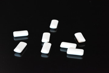 White delicious pillows, chewing gum pillows located on a black glossy surface.