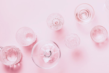 Many empty glasses on pink background. Top view, flat lay