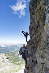 attractive female climbers on a steep Via Ferrata in the Italian Dolomites and having fun