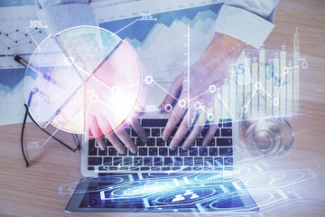 Double exposure of market chart with man working on computer on background. Concept of financial analysis.