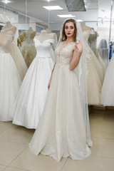 Young girl is trying on beautiful wedding gown in shop