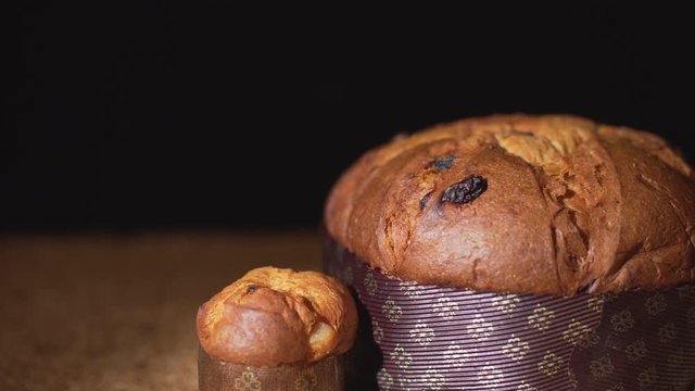 Dolly of delicious and tasty  small and big panettone, an Italian Christmas cake with currants and candie. Food in black background.