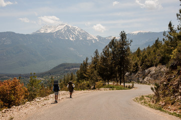 Two people walking on the road with hiking backpacks