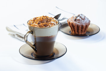 Coffee, cappuccino with whipped cream sprinkled with nuts, ground chocolate and cinnamon. Chocolate muffin in icing sugar. The photo.