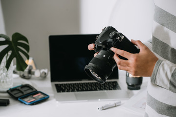 male photographer holding digital camera above the desk in his photo studio