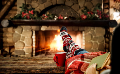 Woman legs with christmas socks and fireplace 