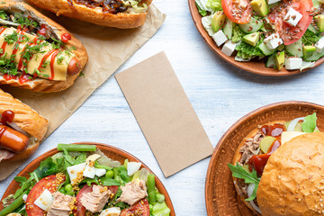 Food photo background with blank craft paper. Composition with hot dogs, burger and salads. Great image for design for street food. Copy space