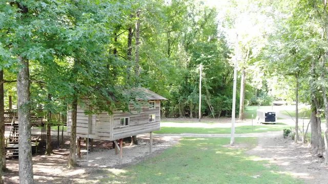 Cabin/treehouse in the woods. Drone closing up on it. Trees surround the cabon