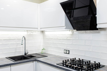 interior of the modern kitchen is white with black furniture and household appliances