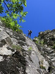 Fototapeta na wymiar alpiniste en descente en rappel avec corde dans une paroi en montagne après l'escalade