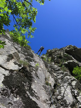 alpiniste en descente en rappel avec corde dans une paroi en montagne apr&egrave;s l'escalade