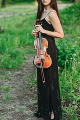 A young woman playing the violin in a magical forest