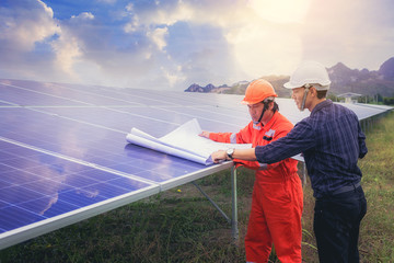 Electrical instrument technician and engineer discussion for use blueprint to plan and maintenance electric system at solar panel field © Panumas