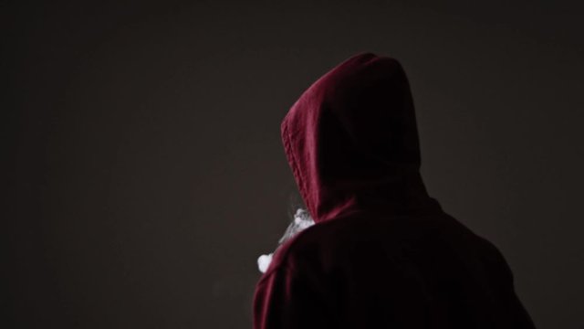 Young male in red hoodie vape puffs multiple smoke rings quickly, slow motion isolated rear view