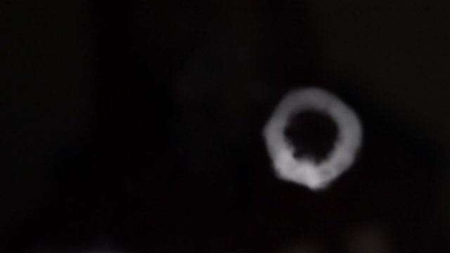 2 smoke vape vortex rings moving towards screen with shallow focus in a dark background, macro close up slow motion isolated