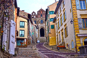 Fototapeta na wymiar Le Puy-en-Velay, France - March 8th 2019 : focus on a medieval street going to the Cathedral. This famous building, departure for Compostela, was built in the XI-XIII centuries in roman style.