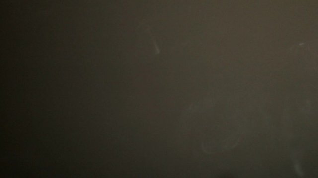 Vortex ring from vape smoke moving towards left in a dark background, slow motion isolated