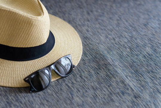 straw hat with black ribbon and sunglasses on sofa wtih free space, vacation travel in summer concept