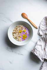 healthy breakfast, a bowl with organic granola, chocolate pieces and vegan soya yogurt on marble background with copy space