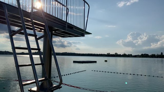 Diving board tower at swiss lake. Shot in 4K of the the Badi in Pfäffikon (Pfaeffikon) Zürich. Showing the lake. Open swimming area.