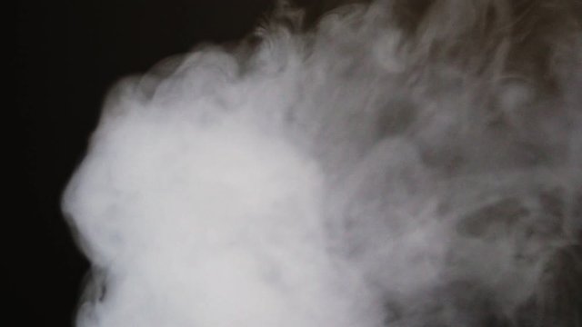 Cloud of exhaled vapor smoke moves across screen as a transition, isolated in dark background, slow motion