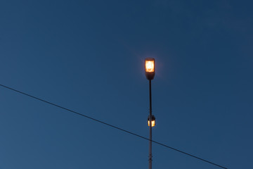 Close-up of a red street light in the dusk blue sky