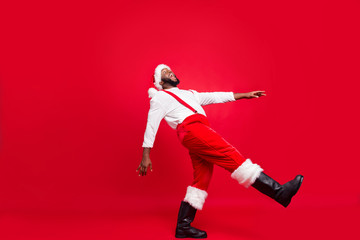 Fototapeta na wymiar Full body profile side photo of cheerful afro american santa claus laughing moving wearing white jumper isolated over red background