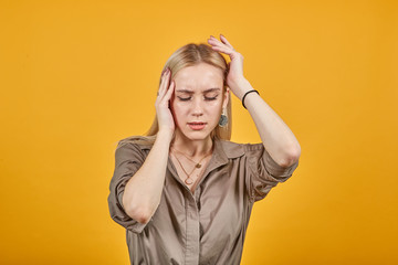 blonde girl in brown blouse over isolated orange background shows emotions