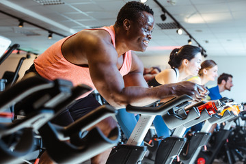 African man and friends on fitness bike in gym