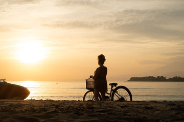 Obraz na płótnie Canvas Girl with bike, silhouette by sunset, sunrise, beach, sky dreamy travel photo