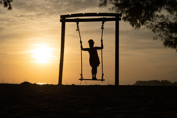 Girl standing on swing, silhouette by sunset, sunrise, beach, sky dreamy travel photo
