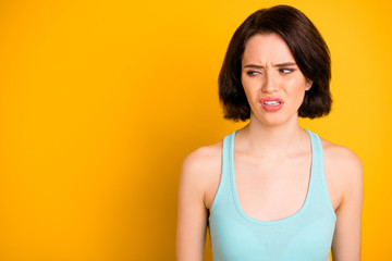 Obraz premium Close up photo of depressed disgusted girl looking at something terrible disdainfully while isolated with yellow background