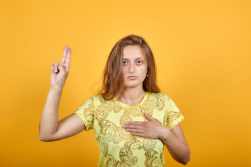 brunette girl in yellow t-shirt over isolated orange background shows emotions
