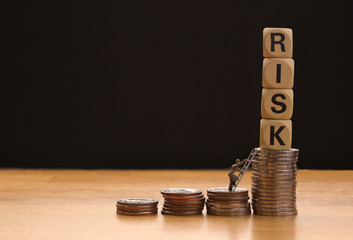 Risk text stacked upward on coins and minature human doll figures climbing as High Risk Business Concept..